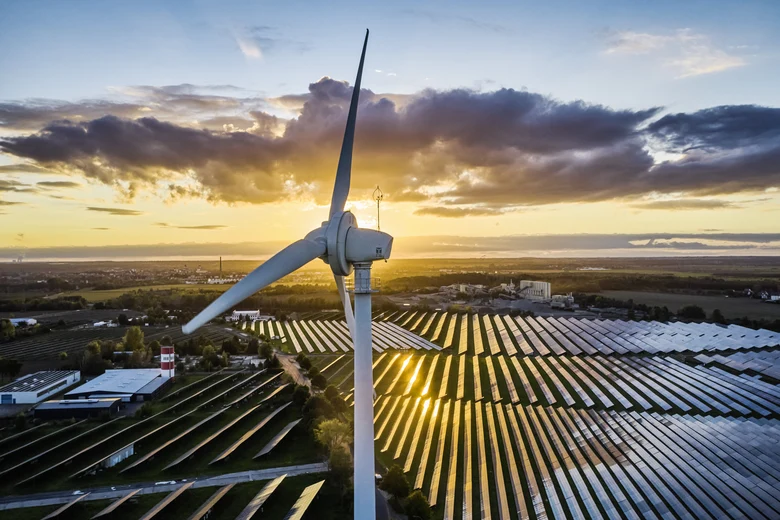 Windrad mit Photovoltaikanlage im Hintergrund