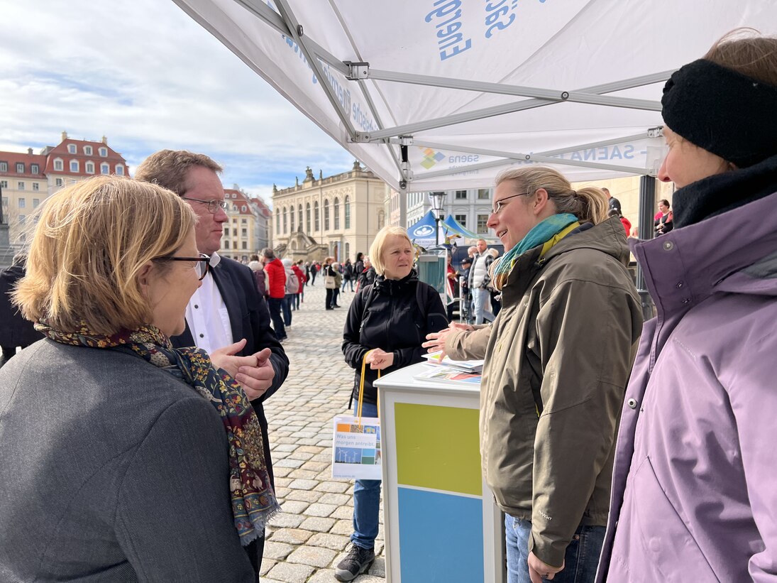 Foto vom Familientag »Energie neu gedacht«: Mehrere Personen im Gespräch an einem Info-Stand der SAENA (Sächsische Energieagentur GmbH)