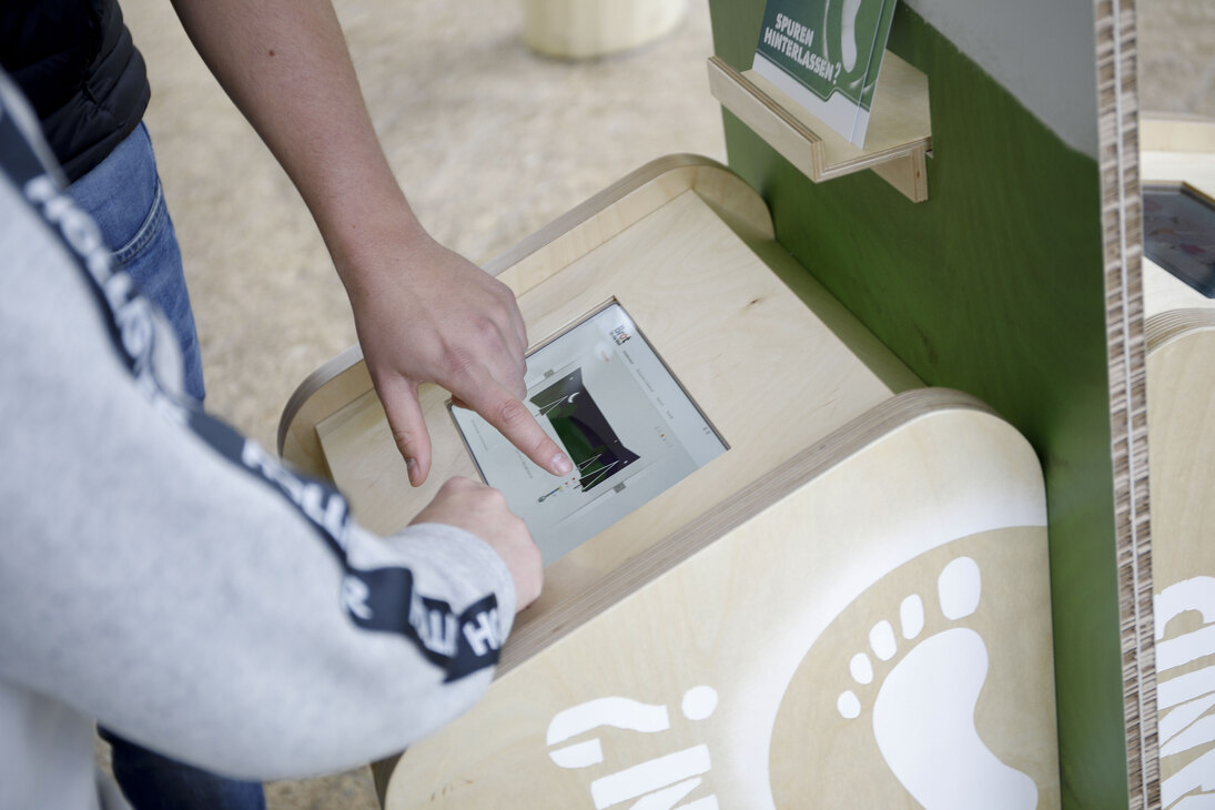 der Ausstellung »Hat Deine Ökobilanz Hand und Fuß?«: Die Hände von zwei Personen bedienen das Tablet am Info-Terminal 