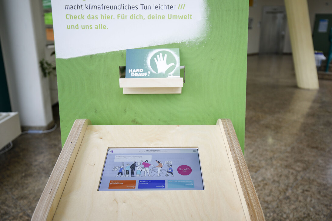Foto vom Info-Terminal der Ausstellung »Hat Deine Ökobilanz Hand und Fuß?«: ein Tablet in einem Tisch aus Holz